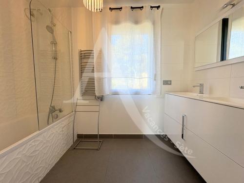 une salle de bain blanche avec une douche et un lavabo dans l'établissement FRONT DE MER 98 M², 3 CHAMBRES, TERRASSE 90 M², à Sète