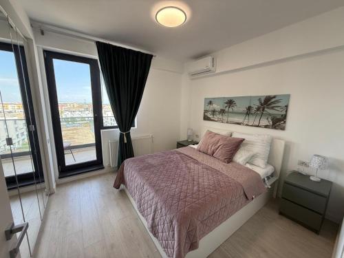 a bedroom with a bed and large windows at Primavera Pipera Plaza in Voluntari