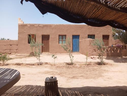a brick building with a blue door in a desert at La Maison-Berbère Mhamid in Mhamid