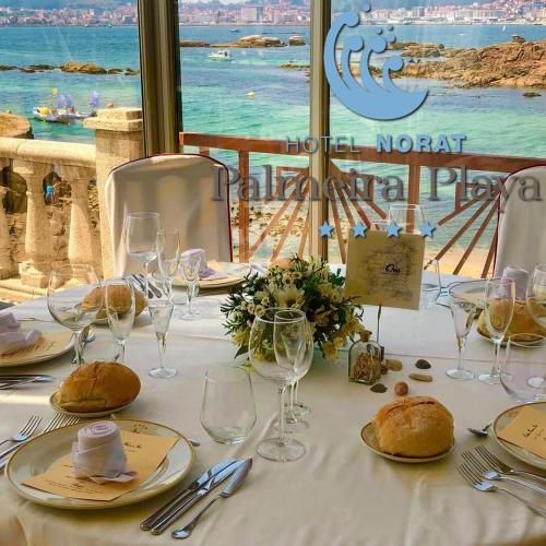 a table with a white table cloth with wine glasses at Hotel Norat Palmeira Playa in Ribeira