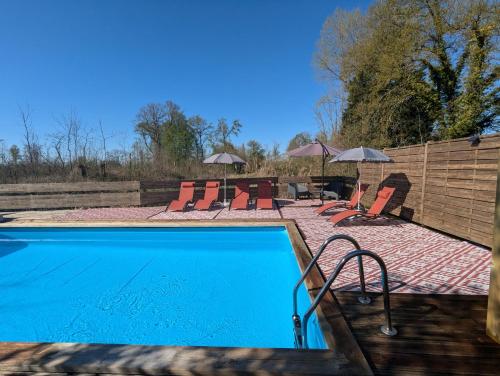 une piscine avec chaises, tables et parasols dans l'établissement Gîte Rue piscine chauffée, à Rue