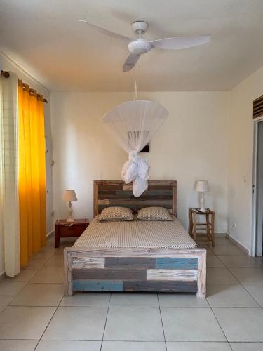 a bedroom with a bed with a ceiling fan at Au Gré des Alizés - Kaz Soley Péyi in Capesterre-de-Marie-Galante