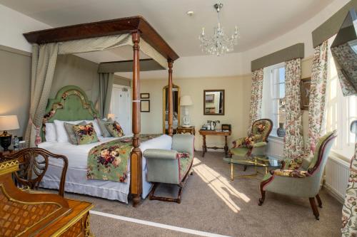 a bedroom with a canopy bed and chairs at The Castle Of Brecon Hotel, Brecon, Powys - The Coaching Inn Group in Brecon