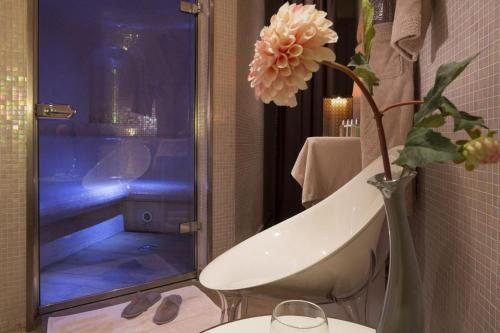 a bathroom with a shower and a vase with flowers at Hotel Le Six in Paris