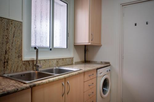 a kitchen with a sink and a washing machine at At503 Ground floor & pool, beach 15min walk away in Comarruga