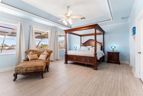 ein Schlafzimmer mit Himmelbett und Sessel in der Unterkunft Villa Estelle - Huge lake front Villa in Cape Coral