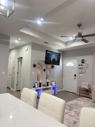 a living room with white chairs and a flat screen tv on the wall at Premier Luxe Villa in Weslaco