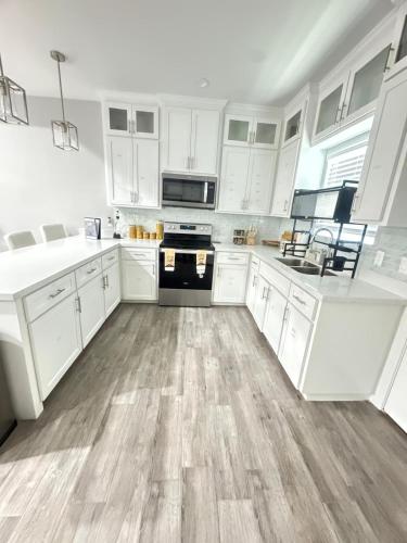 a white kitchen with white cabinets and wooden floors at Premier Luxe Villa in Weslaco