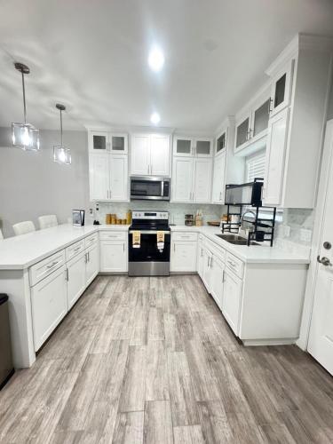 a kitchen with white cabinets and a wooden floor at Premier Luxe Villa in Weslaco