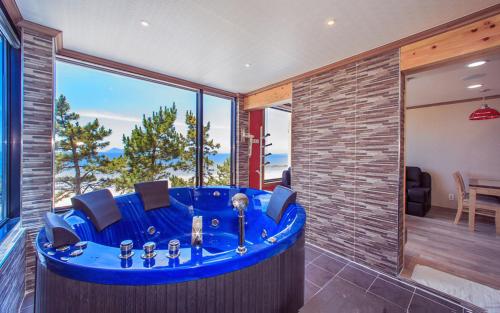 a blue tub in a room with a large window at Soleiview Spa Pension and Resort in Buan