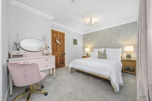 a bedroom with a bed and a mirror and a chair at The Strone Luss Premium Holiday Rental in Luss