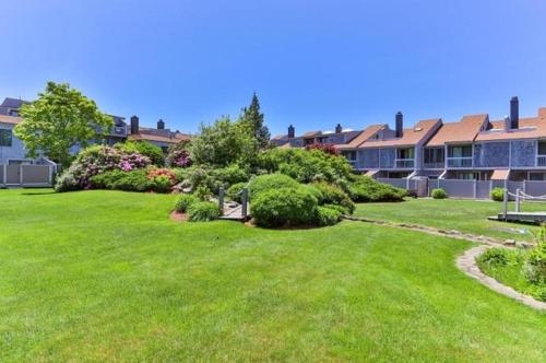a yard of a building with green grass and bushes at Spacious Oceanfront 3BR Condo with Private Beach in Ideal Hyannis Location in Barnstable