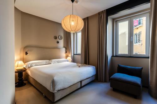 a bedroom with a large bed and a blue chair at Casa Teva Lisboa Boutique Hotel by chic&basic in Lisbon