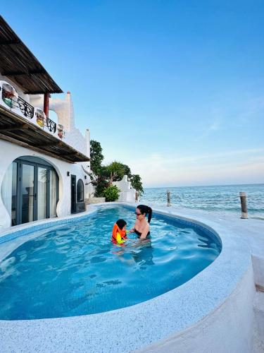 a woman and child in a swimming pool next to the ocean at Santa Fe House - Gành Đá Đĩa in Phú Hạnh (5)