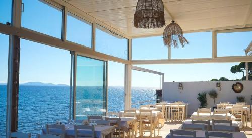 a dining room with tables and chairs and the water at The Painter's Garden, Walk to Sea, Onsite Parking in Nea Makri