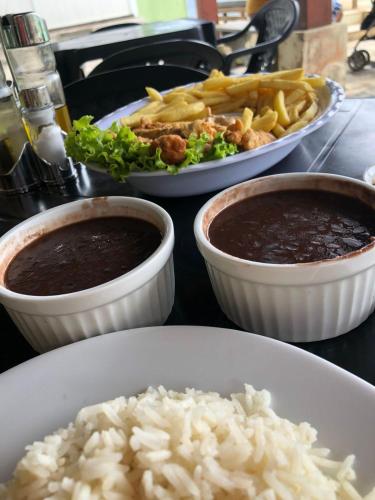a table with three plates of food with rice and beans at Pousada Aconchego de Maricá in Maricá