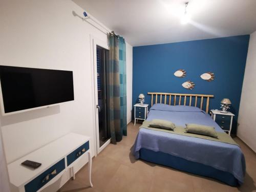 Un dormitorio azul con una cama y un televisor de pantalla plana. en Borgo Celentano, en Torre Lapillo