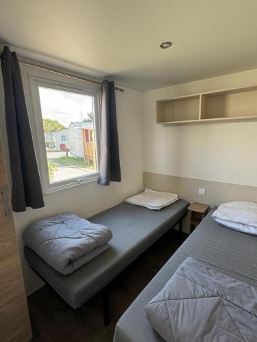 deux lits dans une chambre avec une fenêtre dans l'établissement mobil home 6 personnes accès direct plage, à Canet