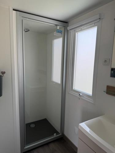 La salle de bains est pourvue d'une douche à l'italienne à côté d'une fenêtre. dans l'établissement mobil home 6 personnes accès direct plage, à Canet