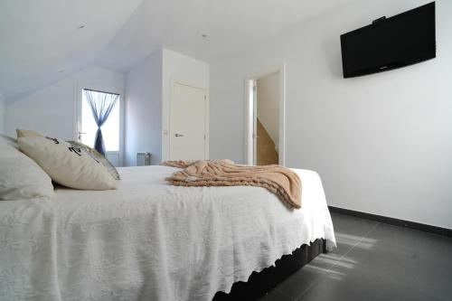 a white bedroom with a bed and a flat screen tv at GALIHOST - Mirando al Mar in Isla de Arosa