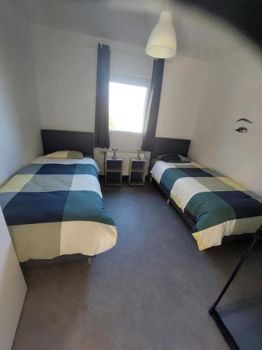 a bedroom with two beds and a window at La Casa Bianca gîte 4 pers in Lierneux