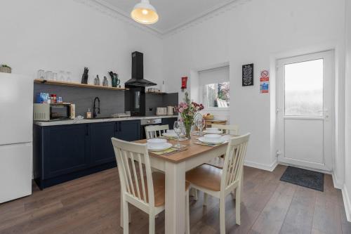 a kitchen with a table and chairs and a kitchen with blue cabinets at Appin House -Cosy 2 bed house in Dunfermline in Dunfermline