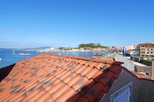 a red roof on a building next to a body of water at GALIHOST - Mirando al Mar in Isla de Arosa