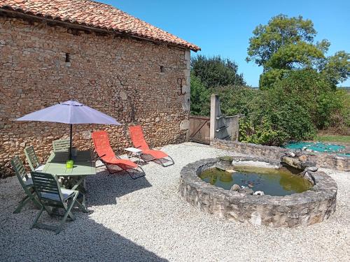 un patio avec une table, des chaises et un parasol dans l'établissement Peaceful unique gite in the countryside, à Javerlhac-et-la-Chapelle-Saint-Robert