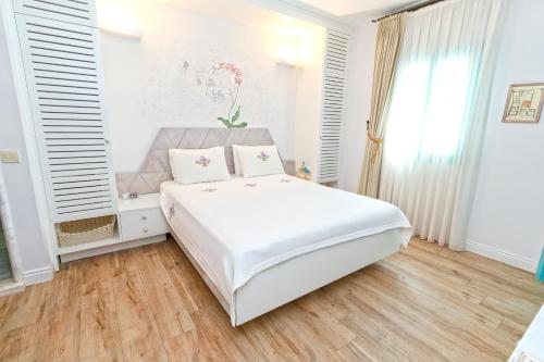 a white bedroom with a white bed and a window at Sigacik Gardenya Buti̇k Otel in Siğacık