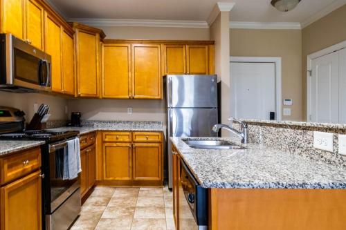 a kitchen with wooden cabinets and a stainless steel refrigerator at The Greensboro Vibe 8715 in Friendship