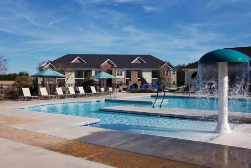 a swimming pool with a fountain in front of a house at The Greensboro Vibe 8715 in Friendship