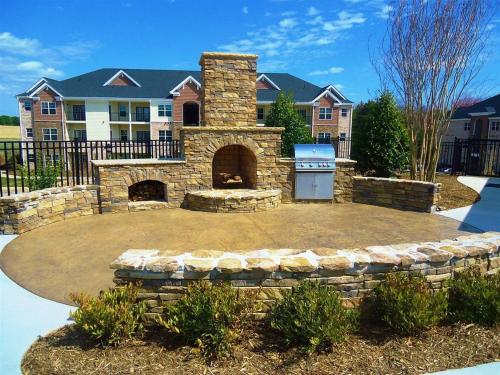 a stone fire pit in a yard in front of a house at The Greensboro Vibe 8715 in Friendship