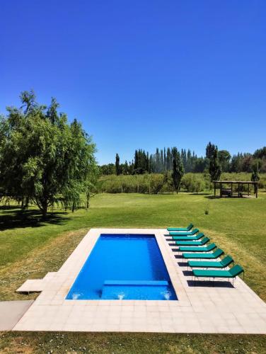 a swimming pool with lounge chairs in a field at Celestino Posta Andina in Barreal