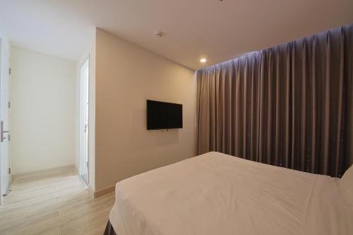 a bedroom with a bed and a television on the wall at Nguyen Le Villa Long Hải in Long Hai