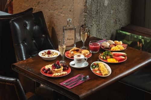 リスボンにあるFigueira by The Beautique Hotels & Spaの食べ物の皿とワインのボトルが置かれたテーブル