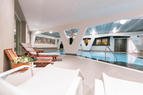 a swimming pool in a house with chairs and a house at Hotel Gran Paradis in Campitello di Fassa