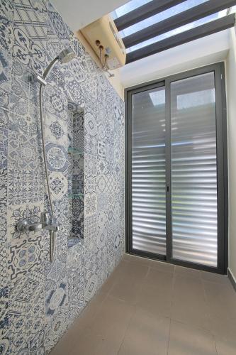 a bathroom with a shower and a tile wall at Nguyen Le Villa Long Hải in Long Hai