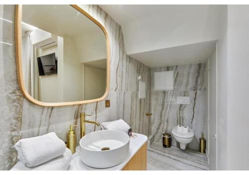 une salle de bain avec un lavabo et un miroir dans l'établissement Apartment Le Marais place des Vosges by Studio prestige, à Paris