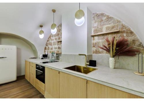 - une cuisine avec un évier et un mur en briques dans l'établissement Apartment Le Marais place des Vosges by Studio prestige, à Paris