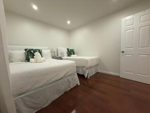 a bedroom with two beds with white walls and wooden floors at Modern Retreat Poconos 3BR Fire Pit Skiing in East Stroudsburg