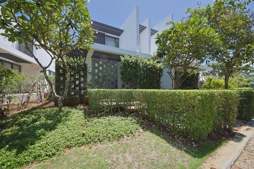 a hedge in front of a house with trees at Nguyen Le Villa Long Hải in Long Hai