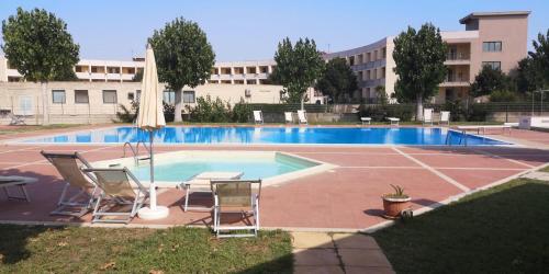 a swimming pool with two chairs and a table at Villetta a schiera su due livelli con giardino in Metaponto