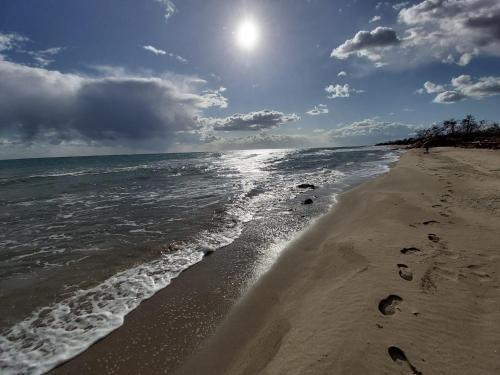 a beach with footprints in the sand and the ocean at Villetta a schiera su due livelli con giardino in Metaponto