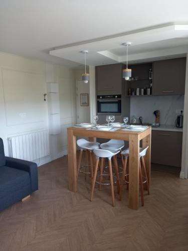 a kitchen with a wooden table and bar stools at Résidences Privées appartements 1 ou 3 entre Varengeville sur mer & Dieppe in Hautot-sur-Mer
