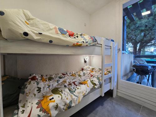 une chambre avec un lit superposé avec un drap avec des animaux dessus dans l'établissement Joli appartement T2 cabine avec parking et wifi Tennis Village, au Cap d'Agde