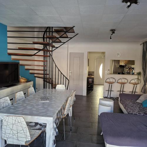 une salle à manger avec une table et des chaises et un escalier dans l'établissement Location Bord de mer, villa de vacances 6-8 personnes - jardin, à Valras-Plage