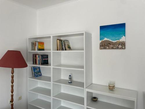 a white book shelf with books and a lamp at Къща за гости НИКА in Kavarna
