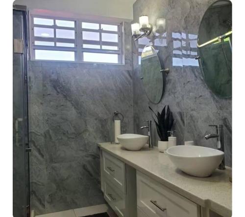 une salle de bain avec deux lavabos et une douche dans l'établissement Cypress Suites, à Goodwill