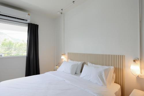 a white bed with white pillows and a window at Lfour phuket in Phuket Town