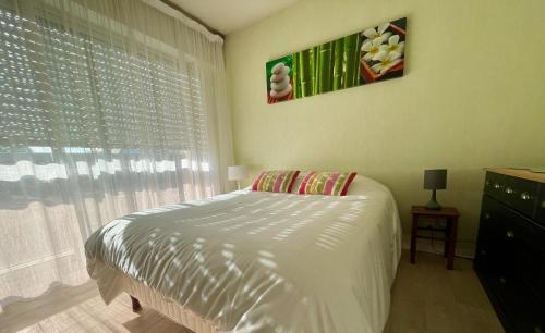 ein Schlafzimmer mit einem weißen Bett und einem Fenster in der Unterkunft Une pause à Bénodet in Bénodet